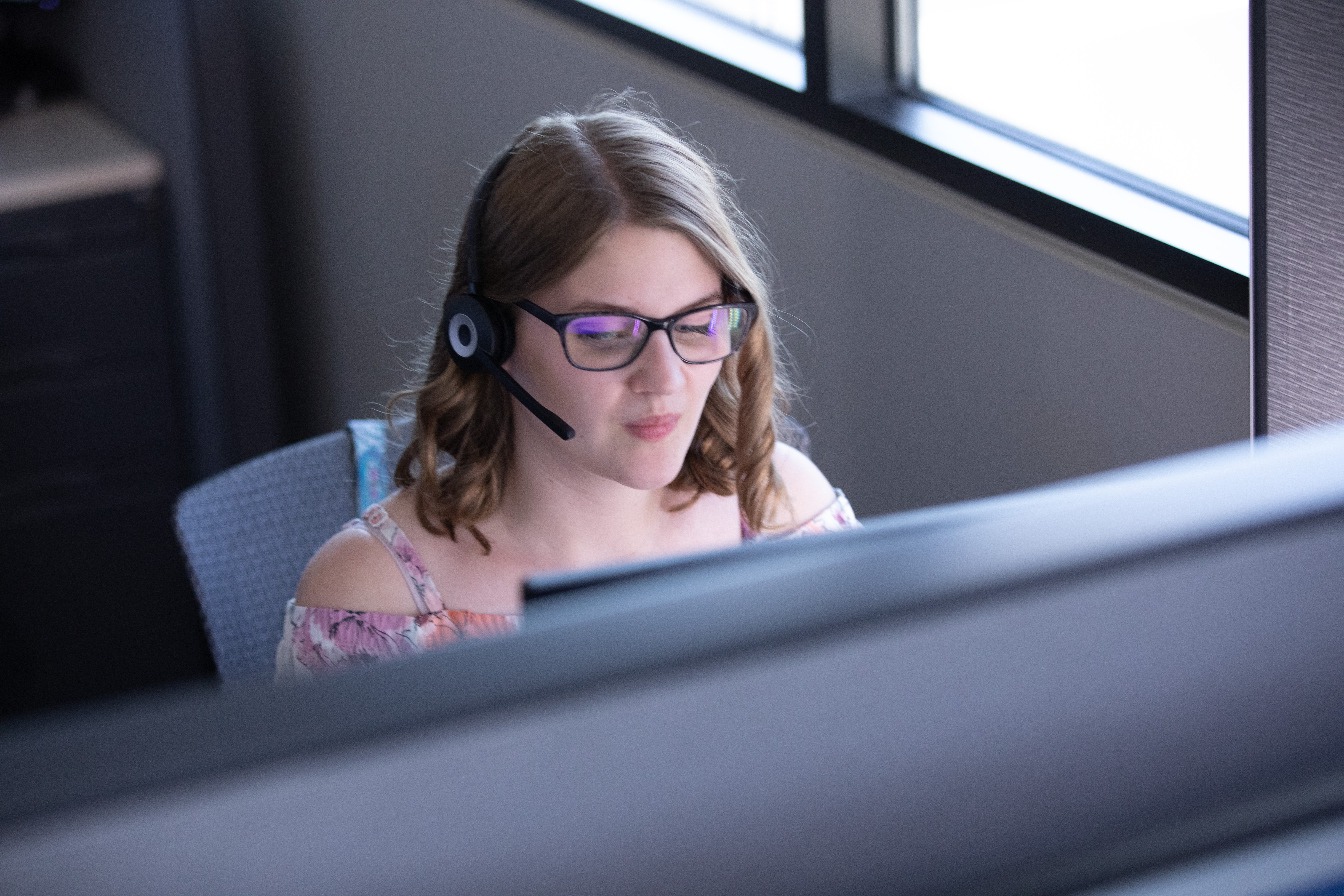 Alison Roets wearing her headset and sitting at the computer in WIC's call center Alison Roets wearing her headset and sitting at the computer in WIC's call center
